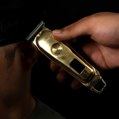 MAC Styler Gold hair trimmer being used on a person's head against a black background